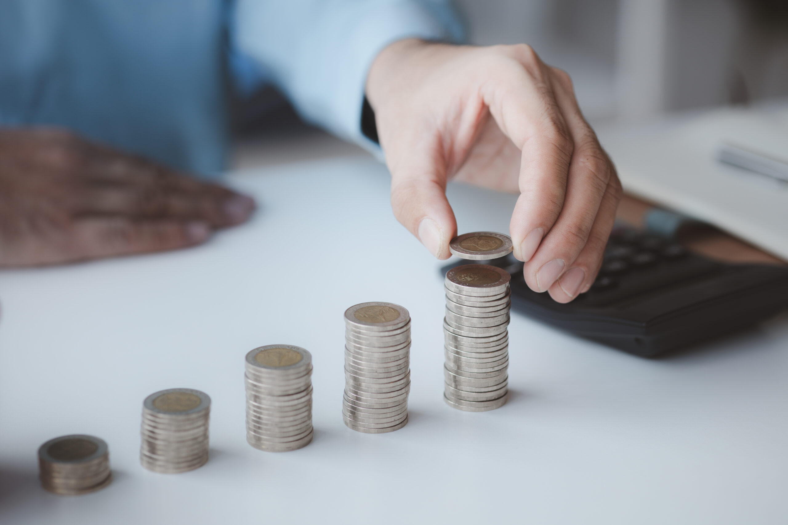 person-with-pile-of-coins-and-piggy-bank-money-sa-2025-01-16-23-43-26-utc-scaled.jpg
